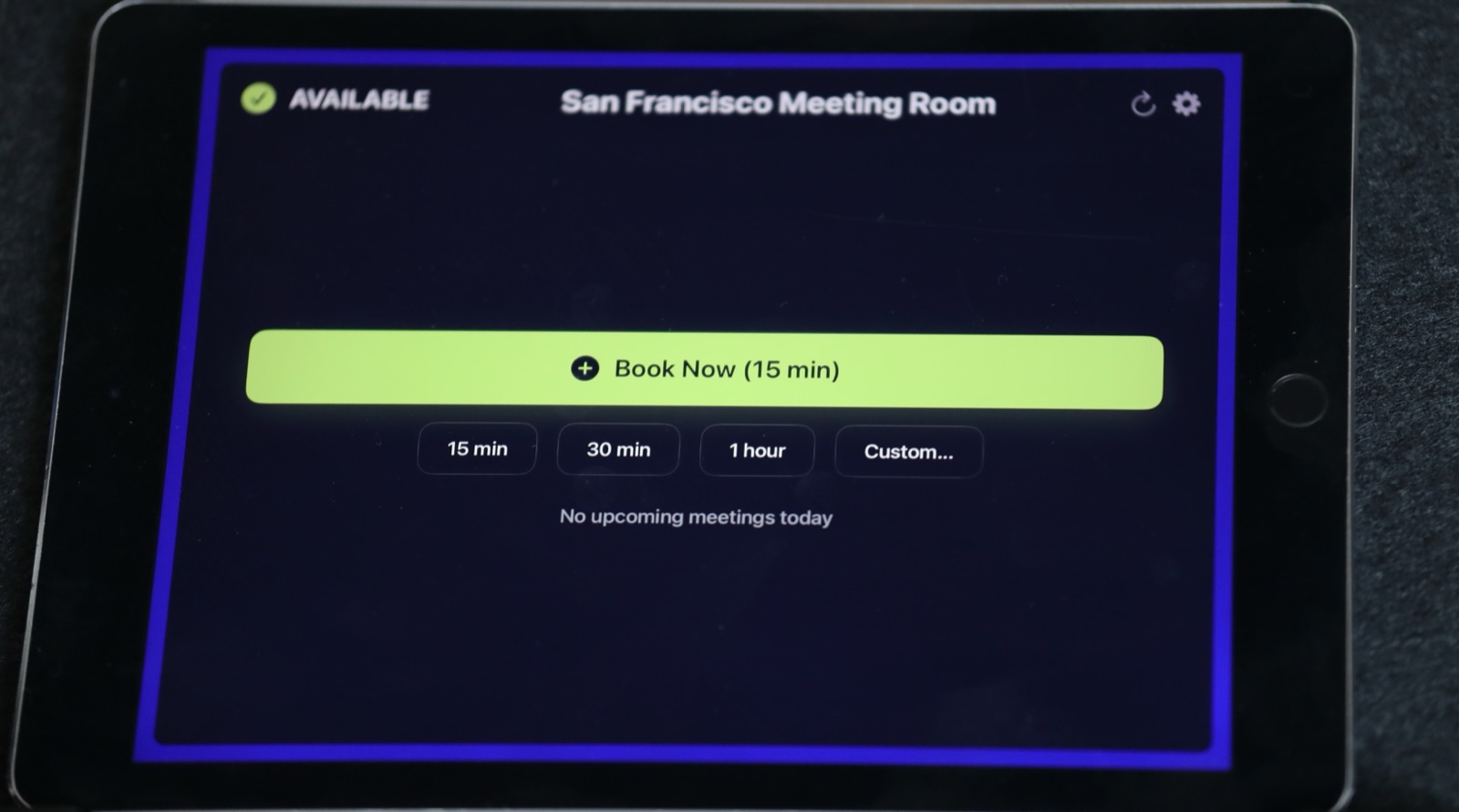 The Room Display muestra una sala disponible con el botón Reservar ahora y opciones de 15/30/60 minutos